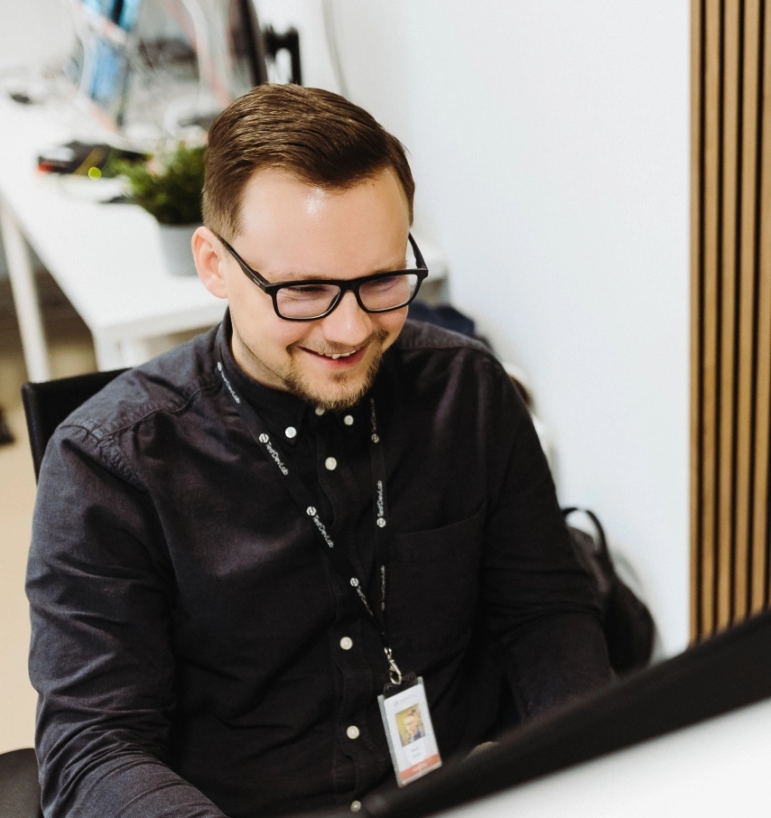 Smiling QA engineer working on a test report on an external monitor