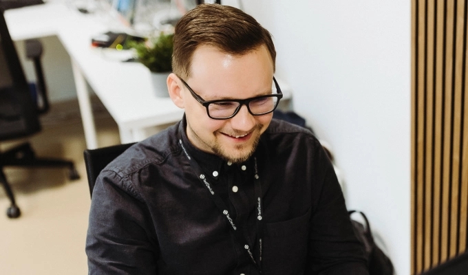 Smiling QA engineer working on a test report on an external monitor