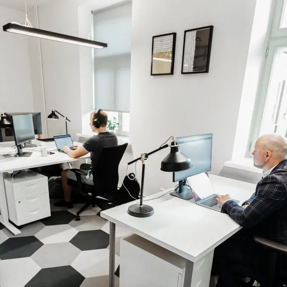 Öppet kontorslandskap med två QA-ingenjörer som sitter vid sina skrivbord.