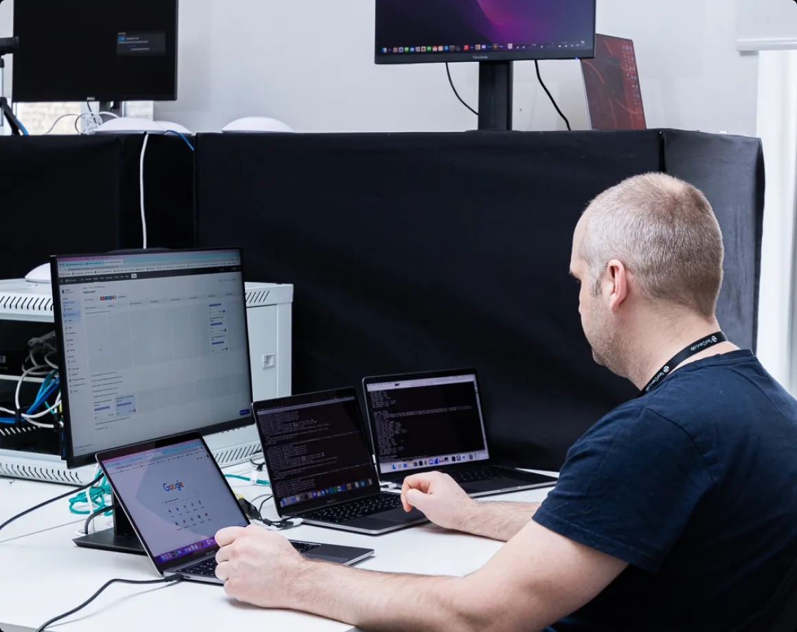 Un ingeniero de QA trabajando con múltiples laptops en un escritorio.