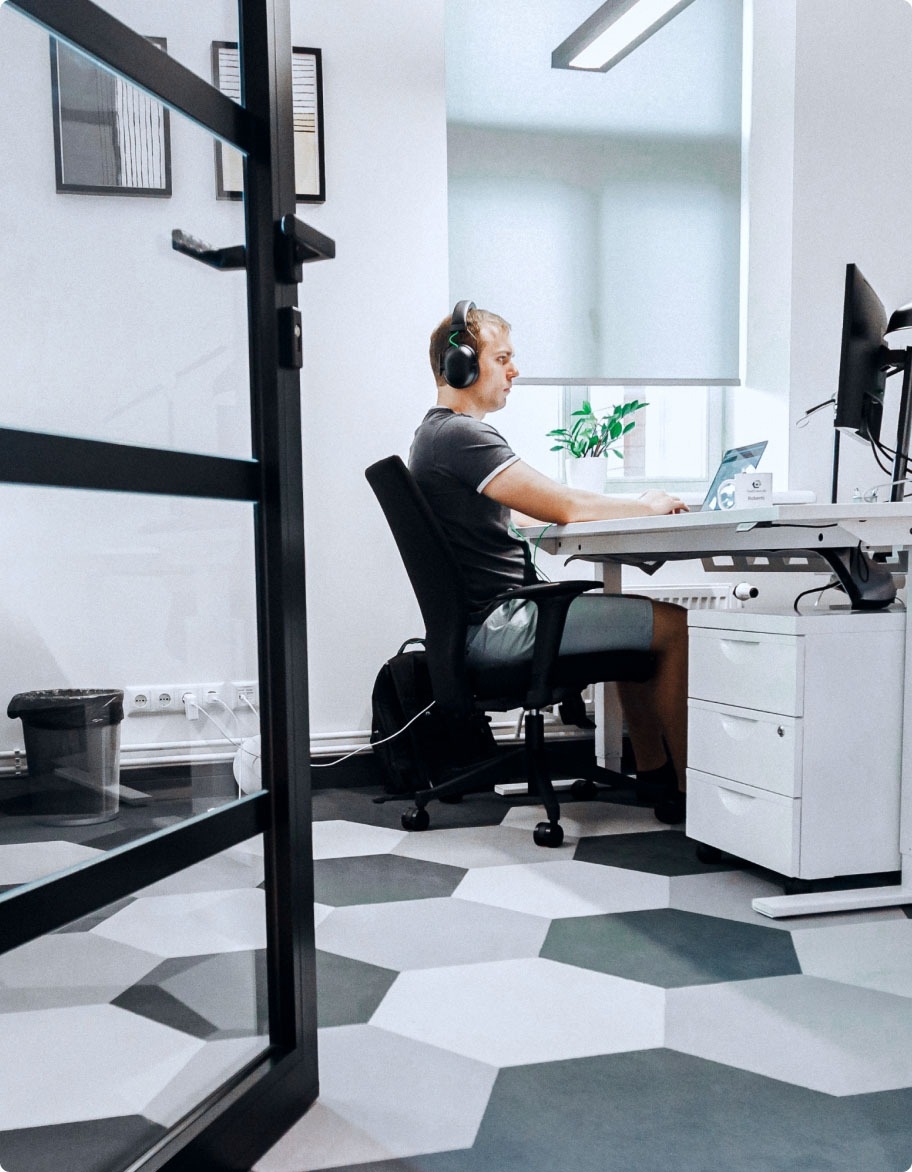 QA engineer sitting at a desk with headphones testing a communications app.