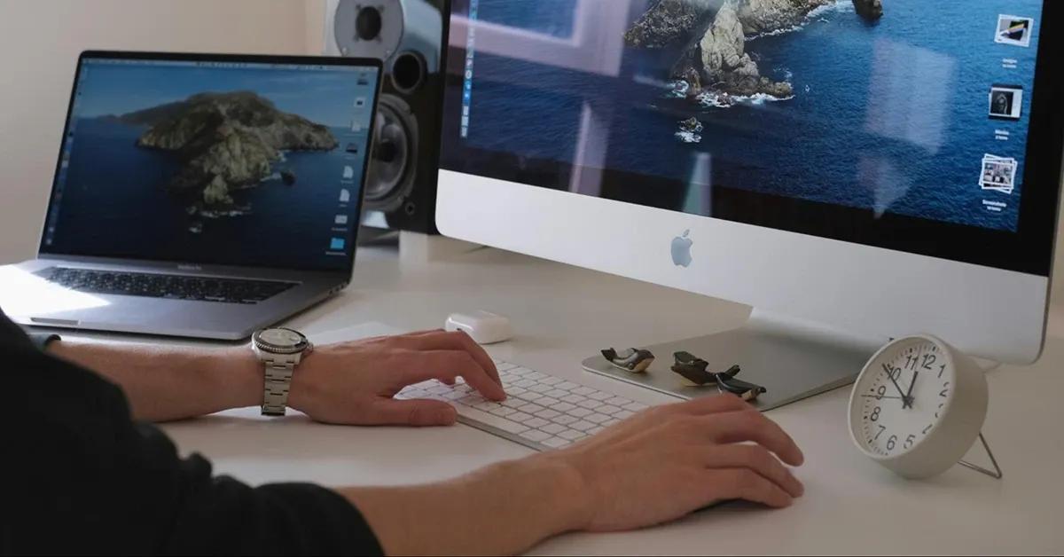 Person working at a desk on a laptop and desktop