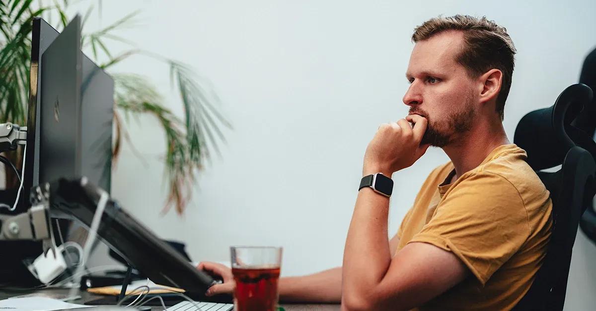 QA engineer sitting at desk looking at computer screen with a serious expression