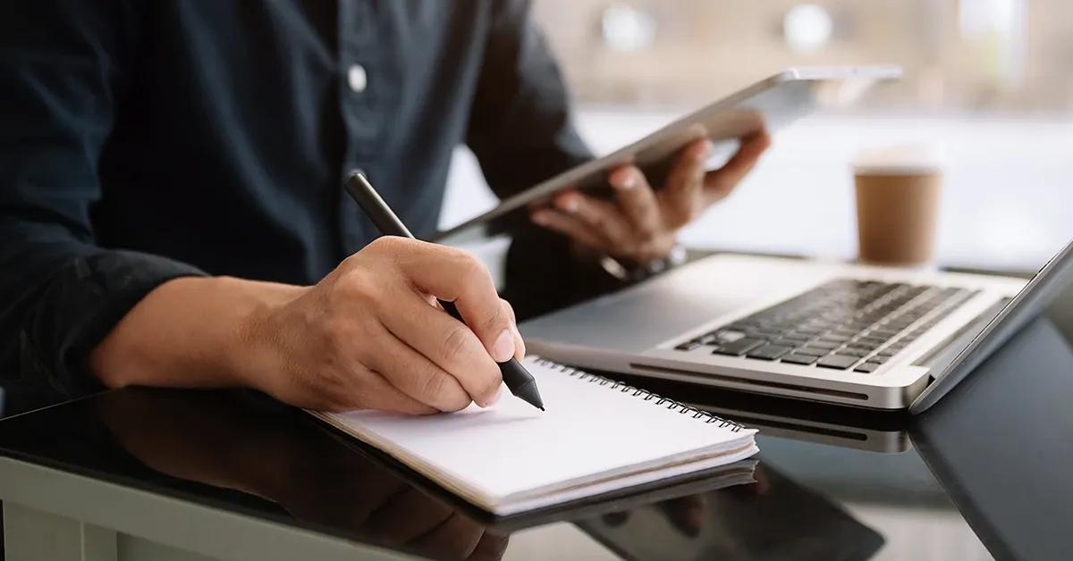 QA engineer performing software testing and writing down notes in notebook