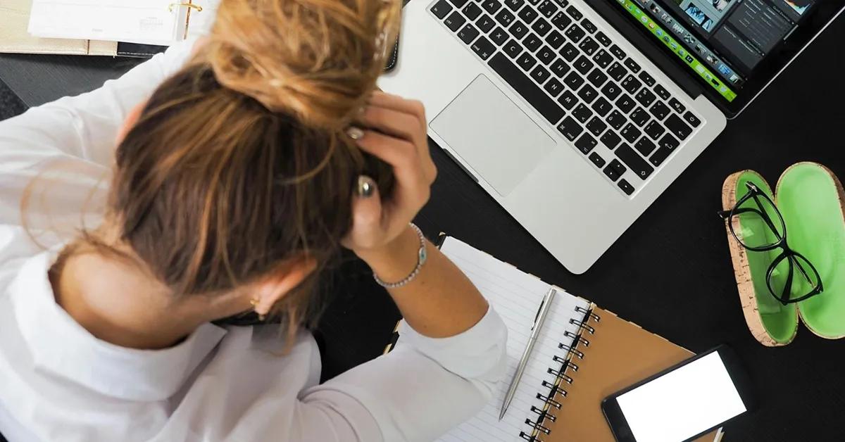 QA engineer sitting at desk holding head in frustration