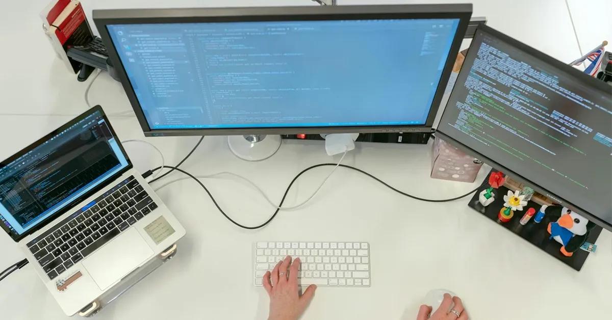 Person shown interacting with two desktop and one laptop computer.