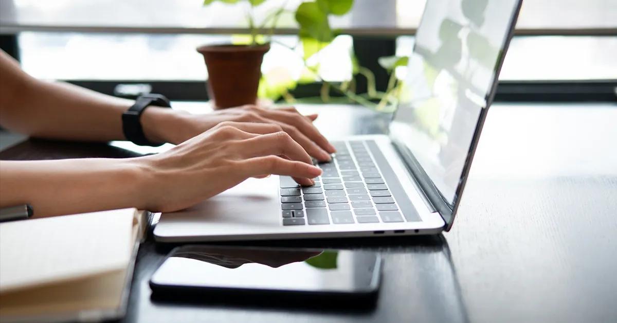 Person at desk typing on laptop computer