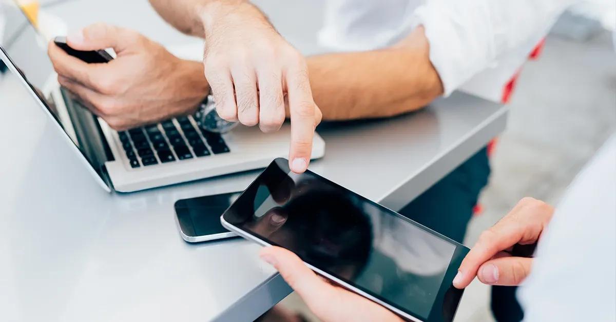 Two people pointing to something on a mobile device that is held by one of the persons