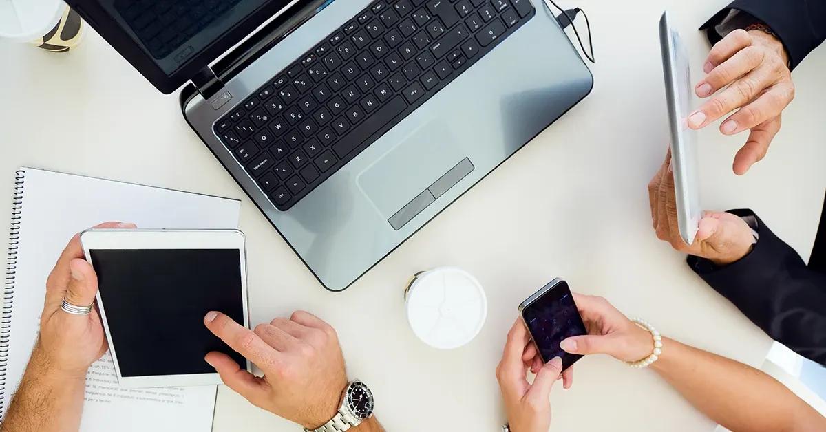 Closeup of three sets of hands using various devices