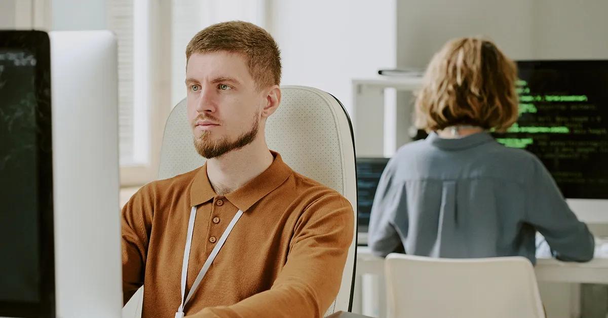 QA engineer facing a desktop computer in an office