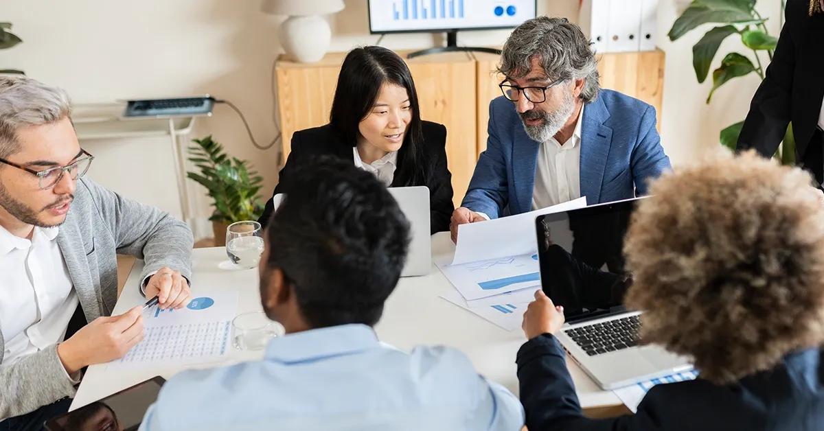 A quality assurance team sitting at desk and talking