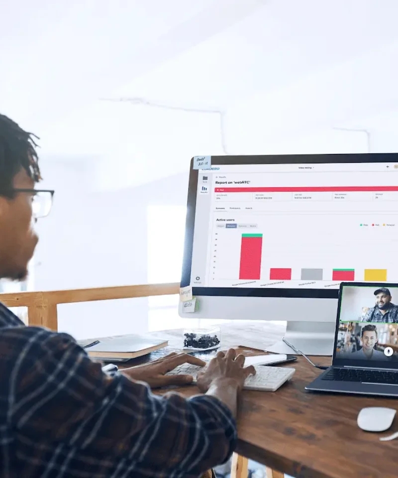 Un professionnel travaillant sur un ordinateur de bureau avec un grand graphique affiché à l'écran, participant à un appel vidéo.