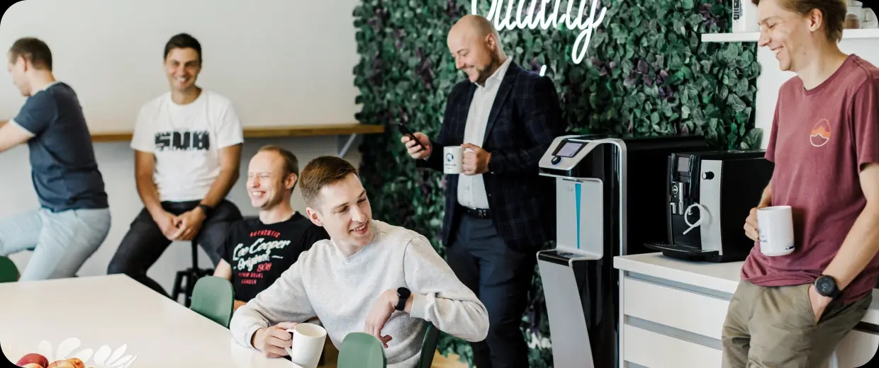 A group of software engineers enjoying a laugh in the office kitchen.
