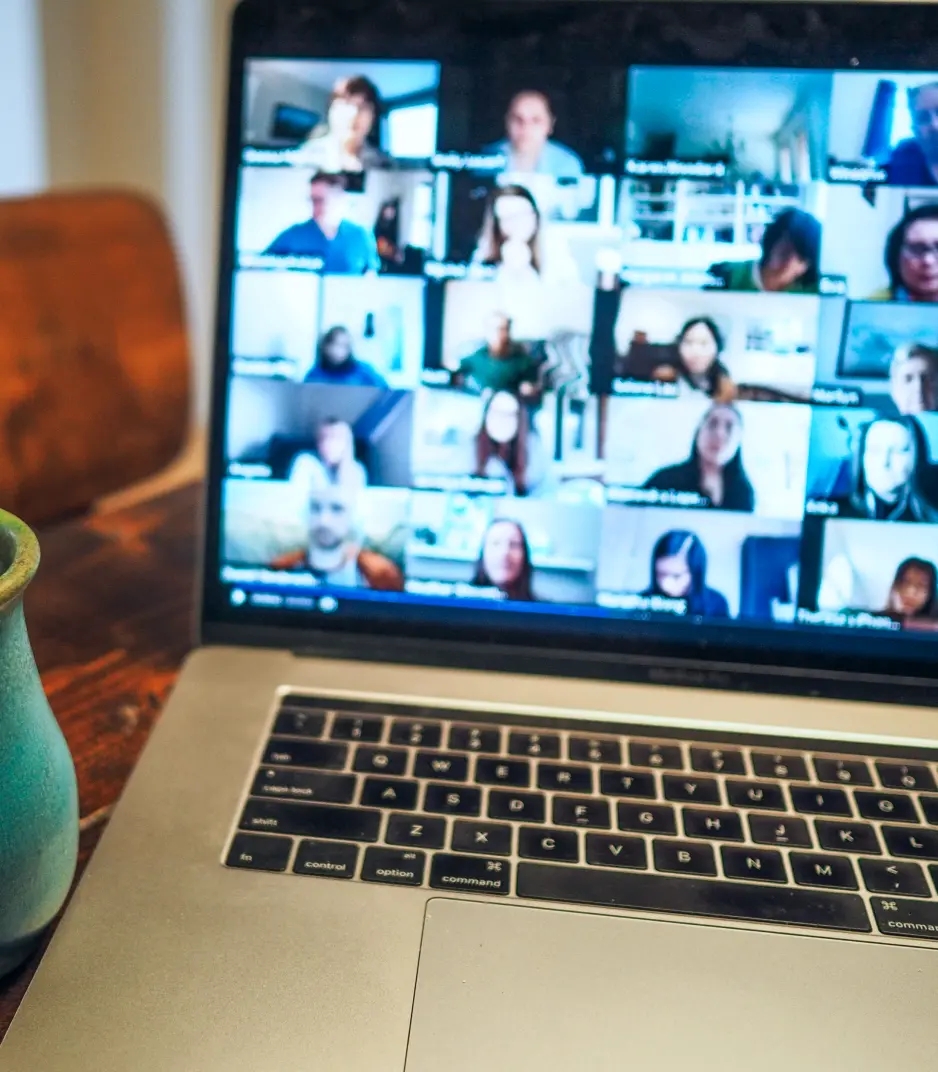 Laptop screen showing a video call with a grid of participants.
