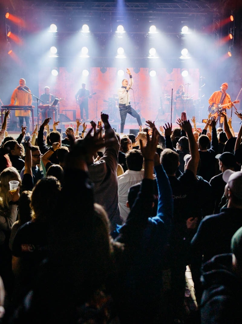 People at a concert listening to a band perform on stage.