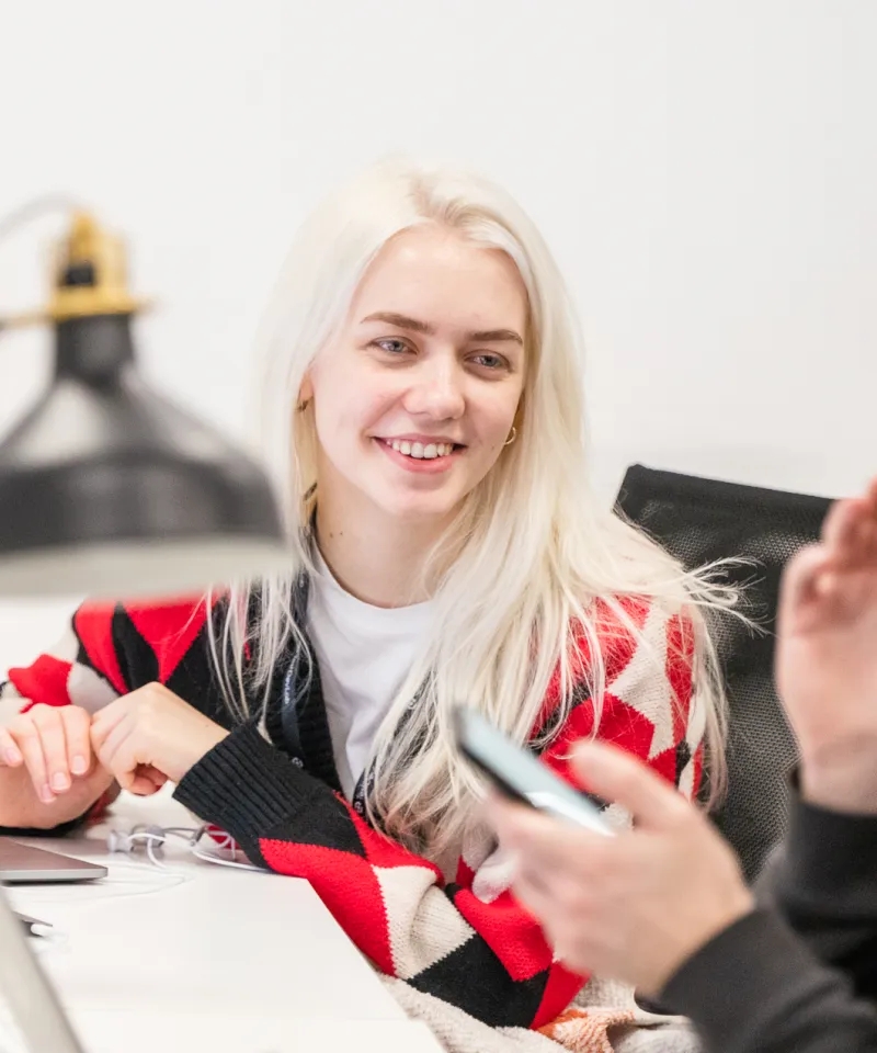 A QA engineer looking at a person holding a phone in the background.