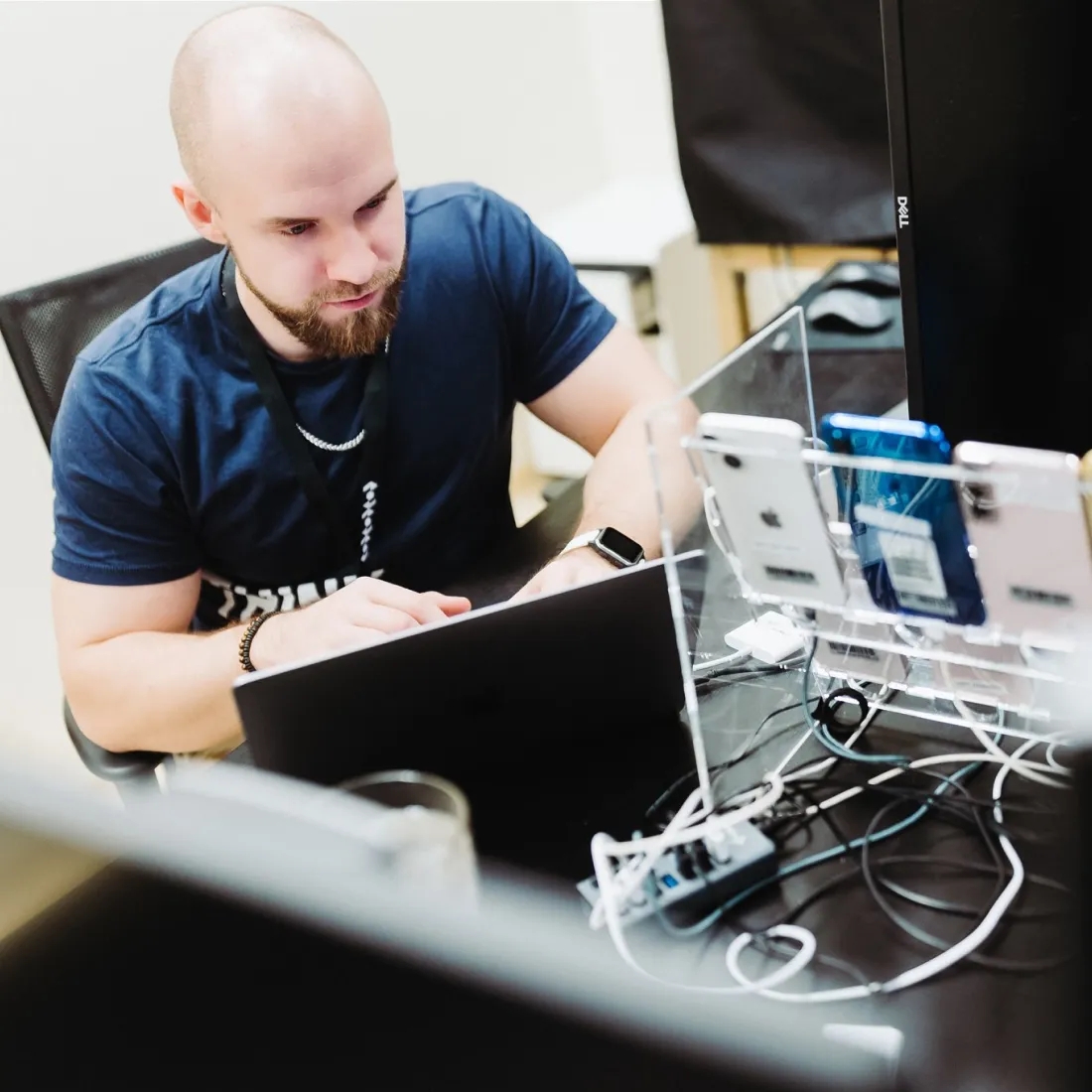 QA engineer sitting at a desk with a laptop and multiple other devices.