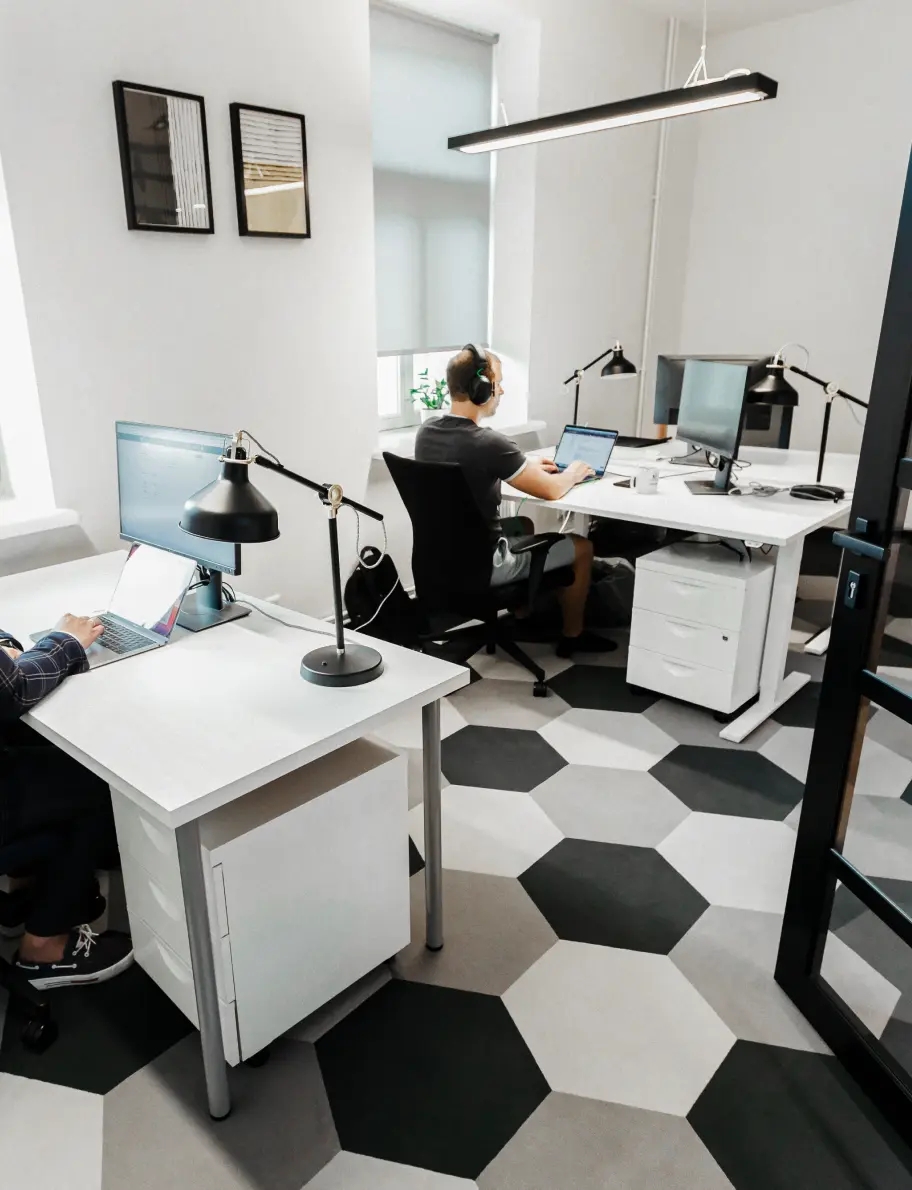 QA engineer sitting at a desk in an office, working on a laptop.