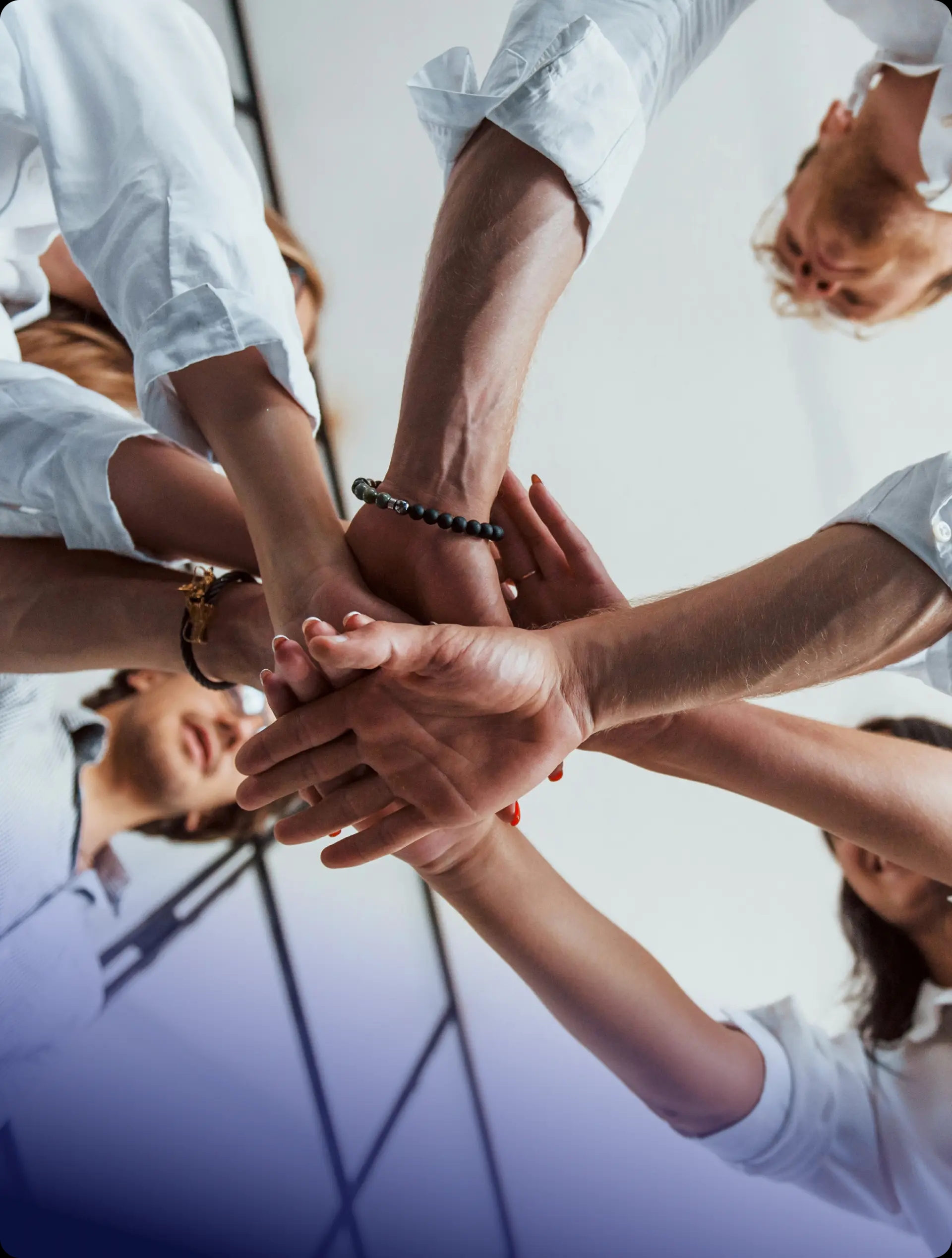 Team members putting their hands together in a circle, symbolizing unity and collaboration.