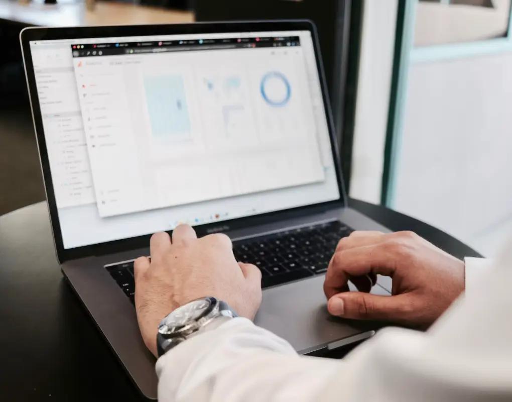 Close-up of a person typing on a laptop that shows an analytics dashboard of charts