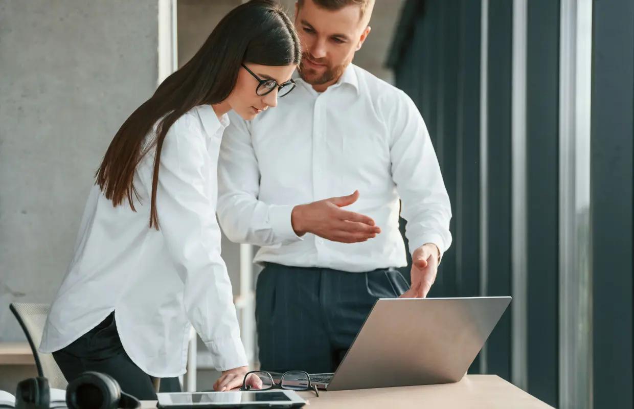 Two colleagues reviewing BFSI software test results together on a laptop