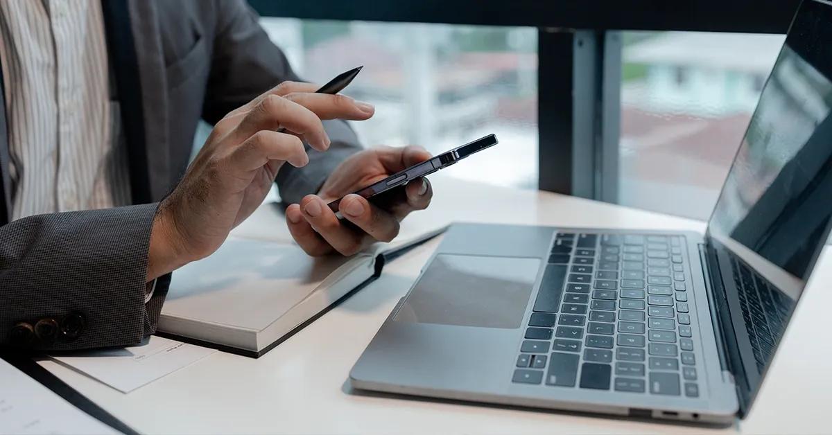 Woman working on her laptop and checking her phone