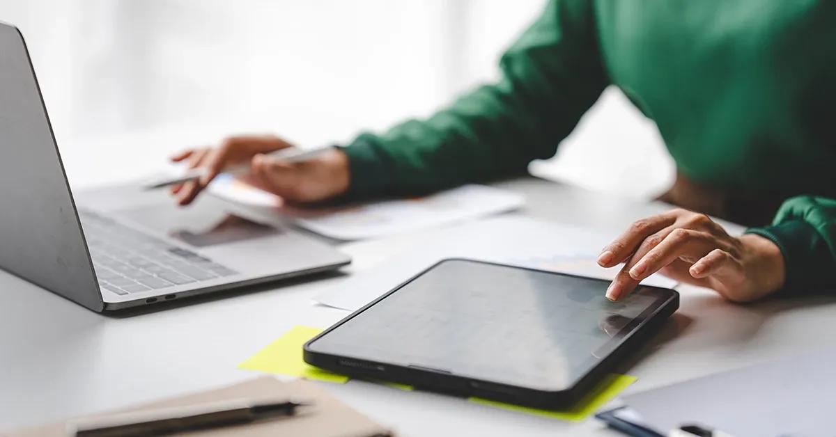 A woman working at her office desk, using laptop and tablet