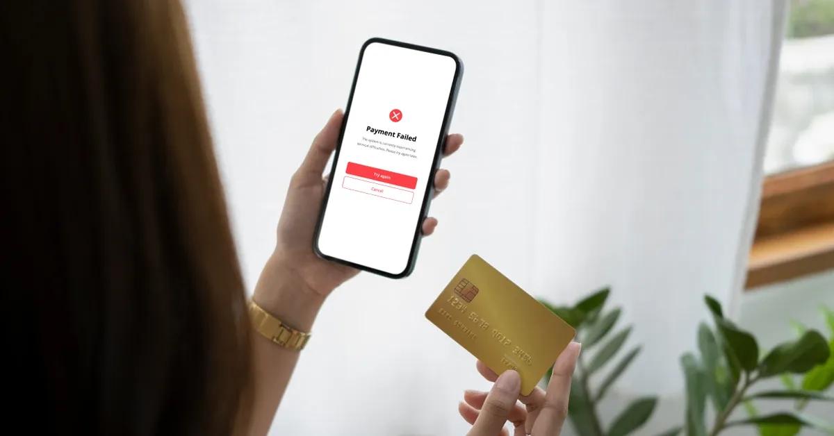 Woman looking at her smartphone displaying 'Payment failed' on screen