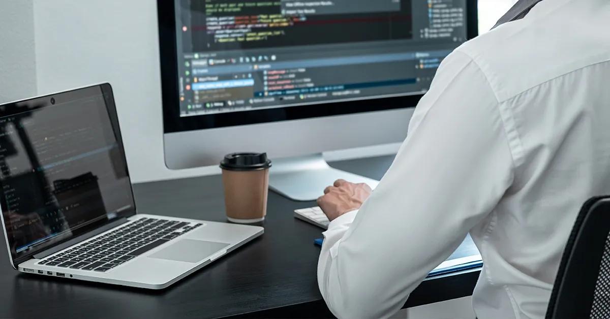 Software engineer sitting at a desk typing on a desktop computer