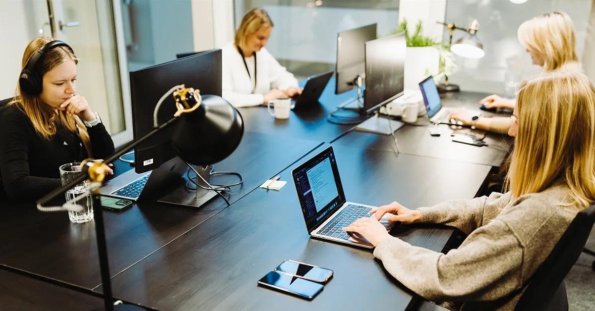 Group of QA engineers sitting in an office working on various devices