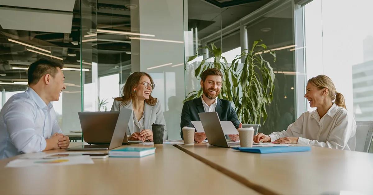 Group of people sitting at a table with their laptops and having a discussion