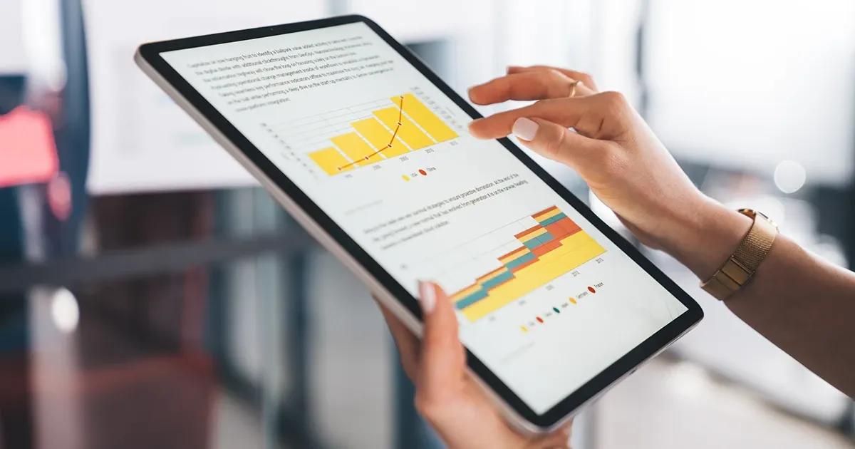 Woman holding a tablet displaying graph charts.